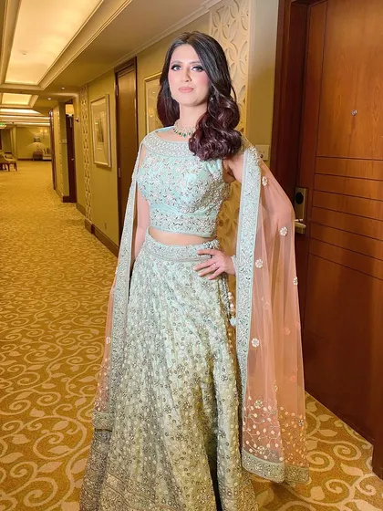 Full view of this gorgeous reception look. The soft mint green lehenga is complemented by a glamorous makeup look with defined eyes and a radiant smile.