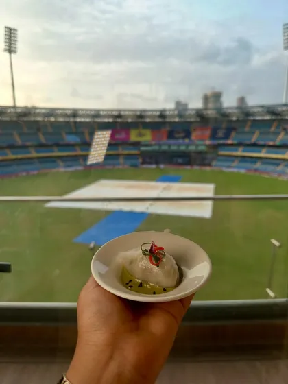 A delicate dumpling held against the backdrop of the Wankhede stadium. A moment of culinary calm before the match.