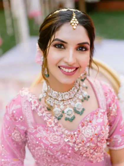 A radiant bride in her pink lehenga, her smile lighting up the frame. A beautiful portrait capturing her joy on her wedding day.