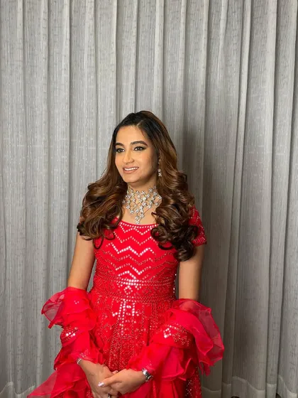 The side-parted voluminous curls add a touch of Hollywood glamour, perfect for a cocktail night or reception.