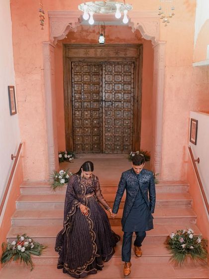 A grand exit or entrance. The couple descends a beautiful staircase hand-in-hand, a cinematic shot that feels like a scene from a royal love story.