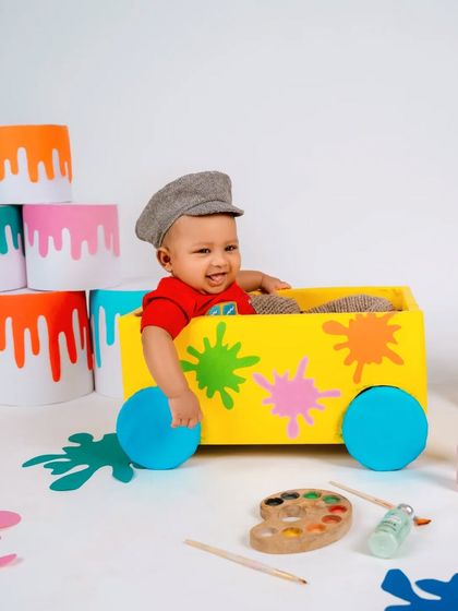 A splash of color for this little artist! This vibrant painter-themed milestone shoot is full of fun props like a colorful cart, paint buckets, and an easel, perfect for a creative baby.
