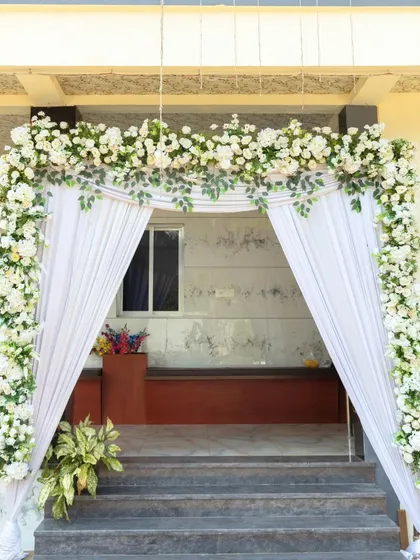 A simple yet beautiful entrance arch with white florals and drapery, offering a classic welcome to the engagement ceremony.