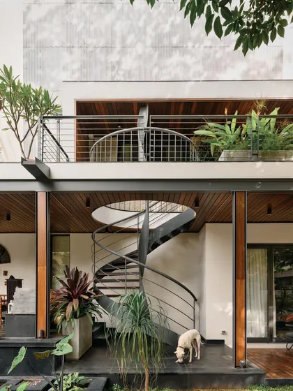 A black spiral staircase provides a secondary, more subtle vertical connection, contrasting with the home's main red staircase.