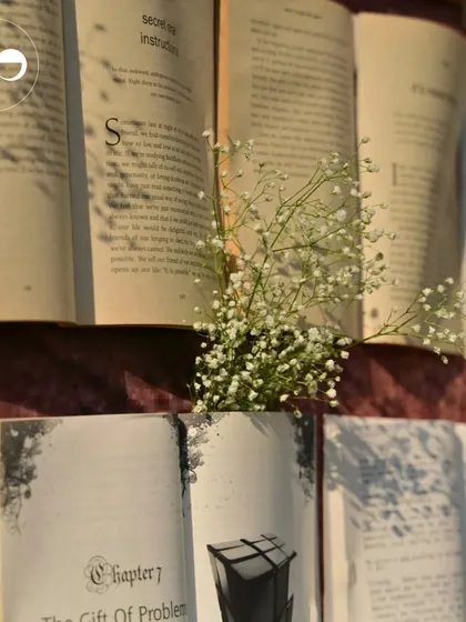 A close-up of the book wall, with delicate baby's breath tucked into the pages, adding a soft, romantic touch to the unique backdrop.