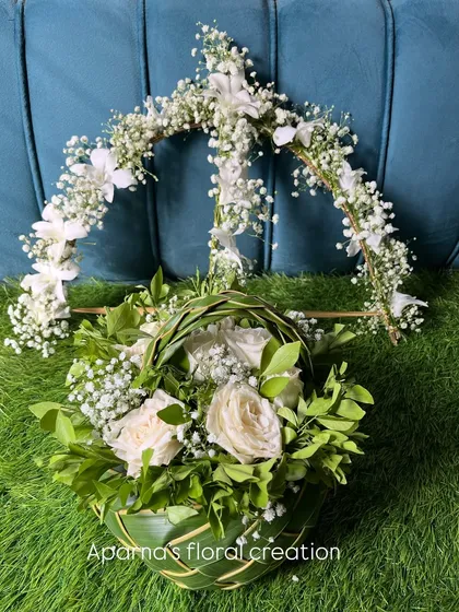 This prop set for a Dohale Jevan includes a Dhanushbaan and a coconut leaf basket, both adorned with fresh white roses and baby's breath for an elegant and traditional look.