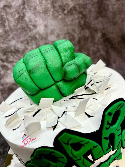 A close-up on the main event: the incredible Hulk fist, sculpted with detailed knuckles and muscles, looking like it's ready to punch through the cake.