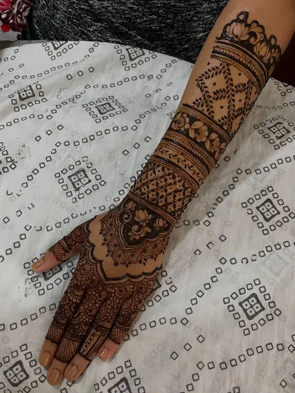 A close-up of one hand, showing the intricate details of the engagement mehendi. The design is a perfect balance of filled and open spaces.