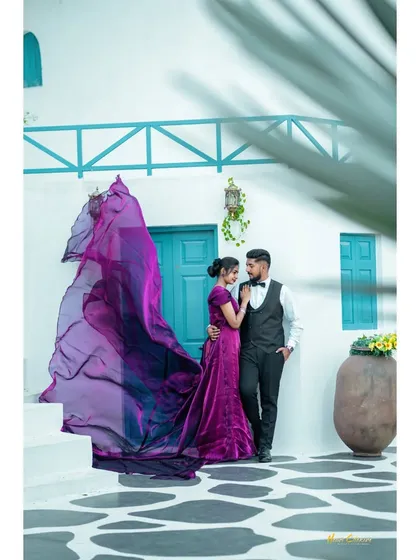 A touch of Greece in India. The couple stands against a classic white and blue backdrop, with the bride's flowing purple gown adding a splash of vibrant color for a perfect Santorini-themed pre-wedding shoot.