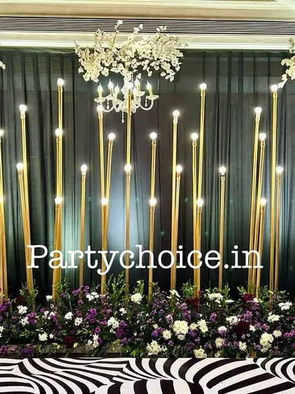 We designed this modern sangeet stage for a glamorous evening. The decor features a dramatic black backdrop, elegant chandeliers, and a series of vertical gold pillars with integrated lighting to create a sophisticated and high-energy ambiance.