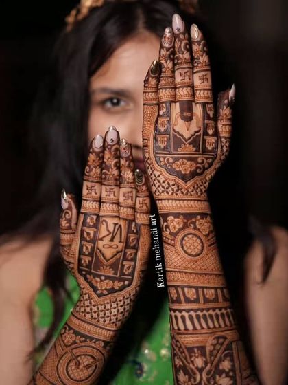 This back-of-hand design for a bride incorporates auspicious symbols like the swastika and Ganpati, along with the couple's initials for a personal blessing.