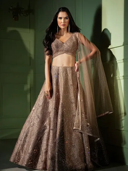 A stunning bronze-gold lehenga with geometric sequin work. The attached cape-style dupatta adds a layer of modern sophistication to this glamorous look.