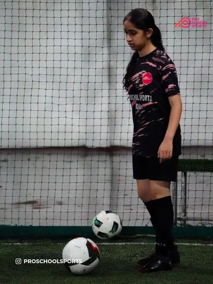 A female player focuses on her ball control during a training session, demonstrating her dedication.