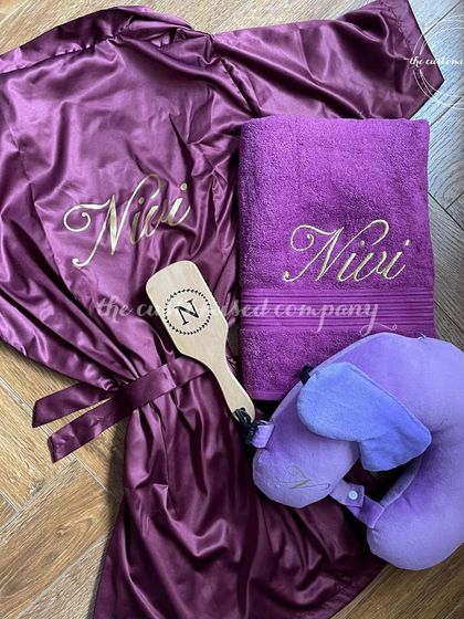 For the bride who loves a pop of color. This gorgeous purple-themed set includes a personalized satin robe, a matching towel, a custom hairbrush, and a comfy travel pillow.