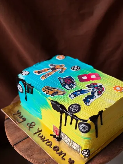 A 2kg Transformers themed cake designed to look like a book. This chocolate truffle cake is decorated with various Autobot and Decepticon toppers.