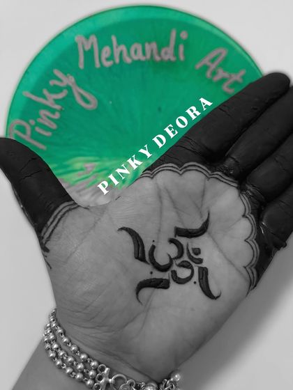 Chanting with art. A simple, bold, and powerful "Om" symbol etched in dark henna on the palm, representing the sound of the universe.