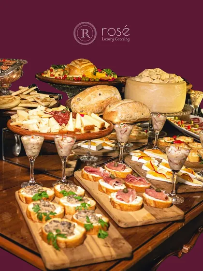 A lavish spread of European-style appetizers and desserts. The table includes an impressive wheel of cheese, artisan breads, bruschetta, and dessert shots, showcasing a truly indulgent offering.