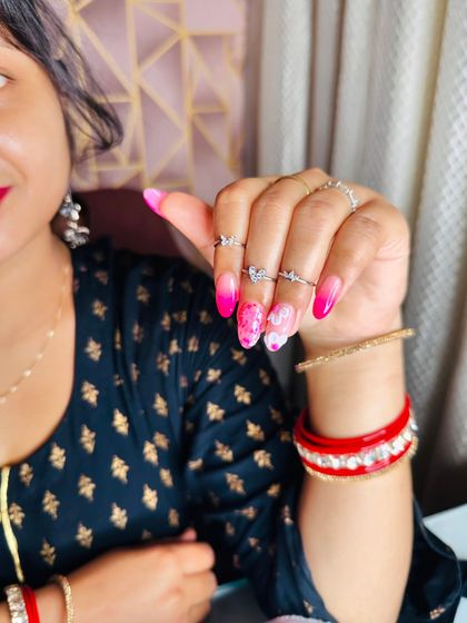 A vibrant pink ombre nail set with glitter and delicate white flower art, perfect for a bright and cheerful look.