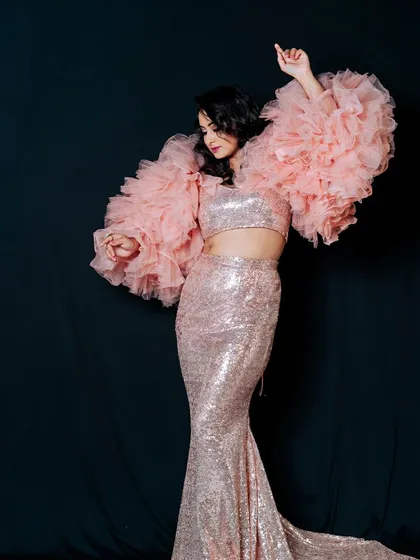 A full-length studio shot that displays the entire silhouette of this glamorous sequin and tulle gown. Posing and lighting were key to capturing the dramatic volume of the sleeves and the elegant mermaid cut of the skirt against a simple dark backdrop.