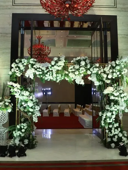 A beautiful floral arch in white and green frames the entrance to the ballroom, offering a classic and timeless welcome for a sophisticated wedding reception.