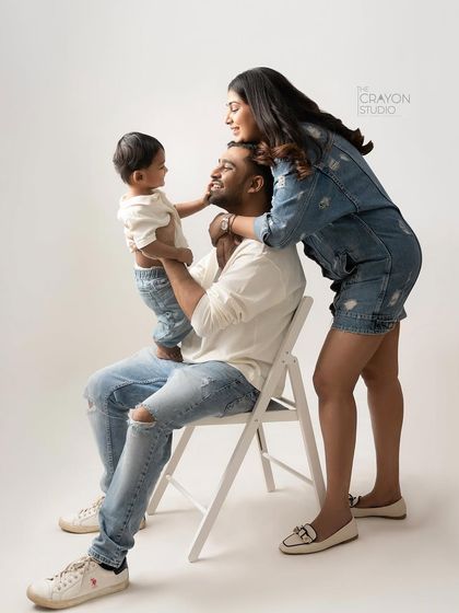 A mother's gentle touch and a father's steady presence create a beautiful frame for their child. This candid studio moment captures the loving dynamic of this young family.