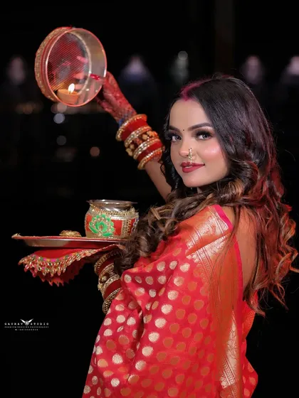 A classic Karwa Chauth pose, with the model holding the sieve and thali.