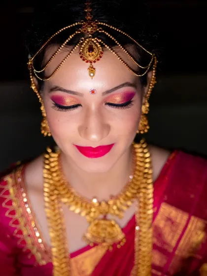 A close-up on the bride's flawless makeup, featuring bold eye makeup and lipstick that complements her traditional attire.
