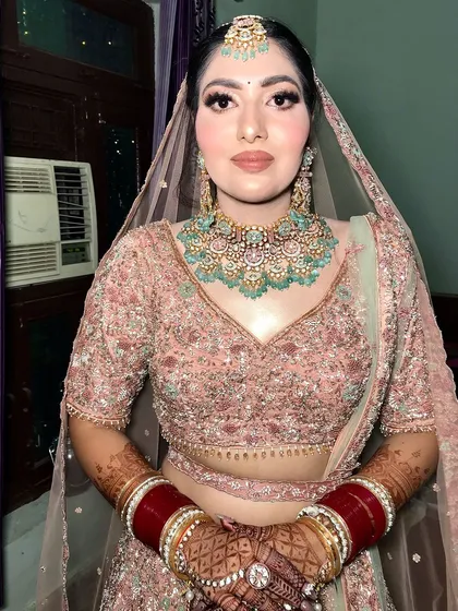 A beautiful bride in a pastel pink lehenga, styled with a contrasting mint-green kundan jewelry set.