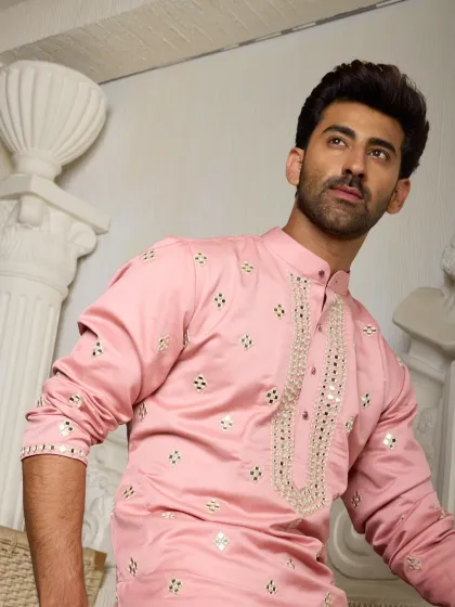 A blush pink kurta adorned with shimmering mirror work and delicate gold embroidery along the placket. This piece is the epitome of understated luxury, perfect for daytime celebrations.