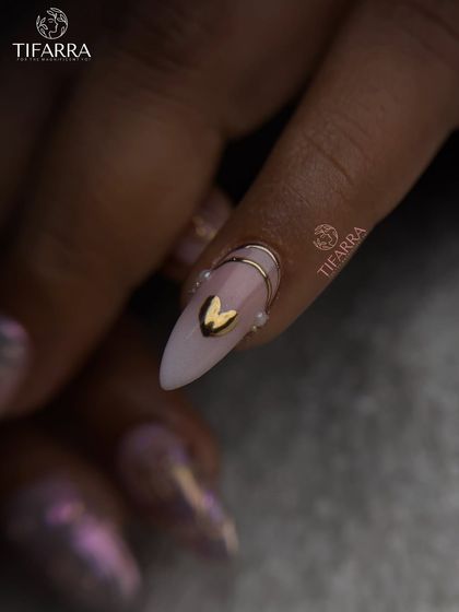 A minimalist accent nail featuring a 3D golden heart and a delicate gold band, adding a sweet touch to a bold set.