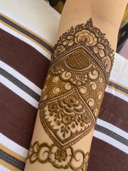 A special cuff design for the sister of the bride. This intricate band features architectural and floral elements, creating a unique and beautiful piece of jewelry-style mehendi.