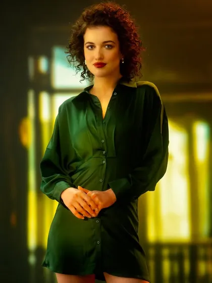 A colorful, abstract, out-of-focus city scene at night, created with projection. The bokeh and color blend to create a dynamic and modern backdrop for this emerald green dress.
