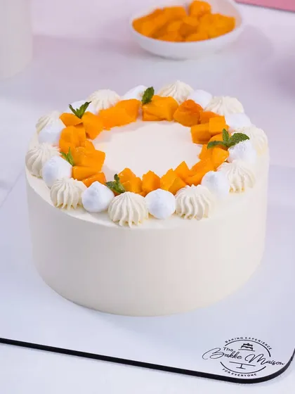 A beautiful mango cake decorated with fresh mango pieces and mint. This is a perfect example of a hero shot for a seasonal special.