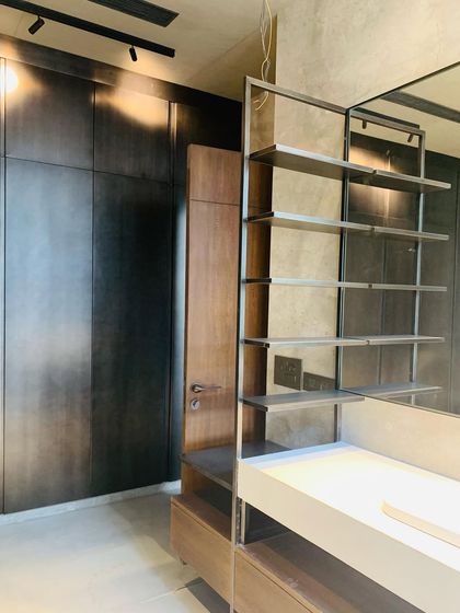 A custom shelving unit in a walk-in closet, combining dark metal framework with warm wood. The design is both functional and visually light, with an open structure and integrated lighting.