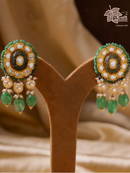 When light chooses luxury. These Moissanite Mirage earrings, studded with handpicked moissanite stones and accented with emeralds and pearls, showcase exceptional Kundan craftsmanship in 22-carat gold.