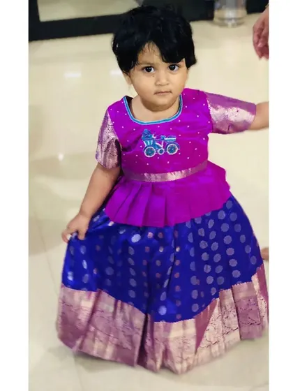 I love adding a playful touch to traditional wear. For this classic Pattu Pavadai, I designed a modern peplum blouse and added a cute, custom hand-embroidered bicycle, a little detail just for her.