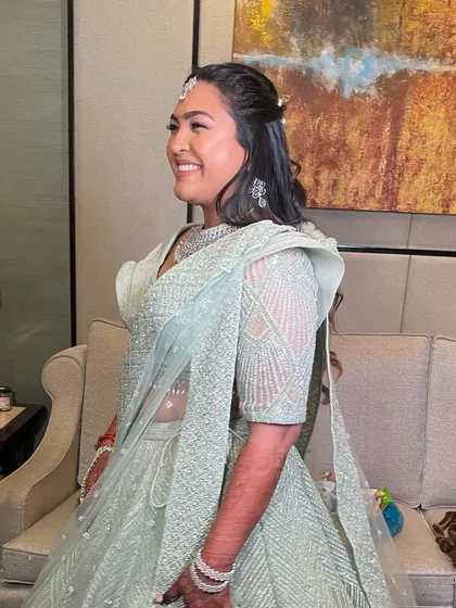 A smiling client showing off her beautiful half-updo with curls.