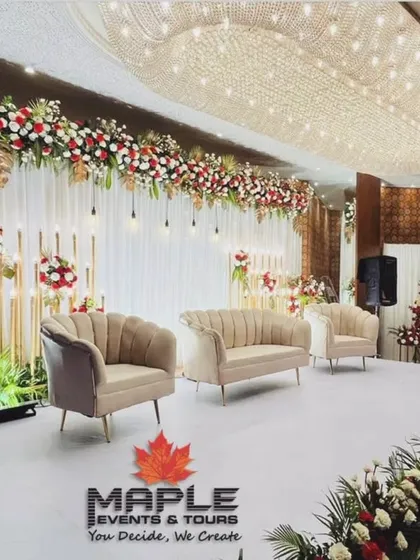 A wide view of a luxurious reception stage, showcasing the grand scale of the floral decor under an expansive crystal chandelier. The clean white stage floor reflects the light beautifully, enhancing the opulent atmosphere.
