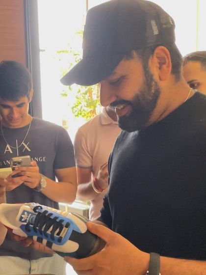 Rohit Sharma smiling as he inspects the details on his custom Adidas sneakers.
