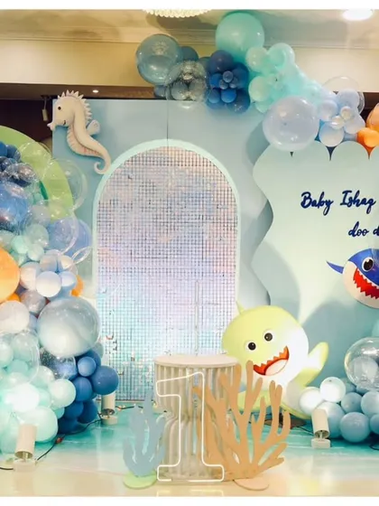A fun and colorful "Baby Shark" themed first birthday. The decor features characters from the popular song, an underwater backdrop, and a sea of blue and orange balloons.