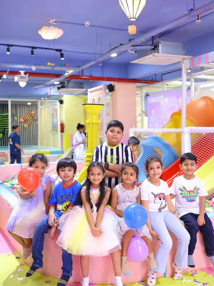 A group of friends posing for a photo by the ball pit during a butterfly-themed birthday celebration.