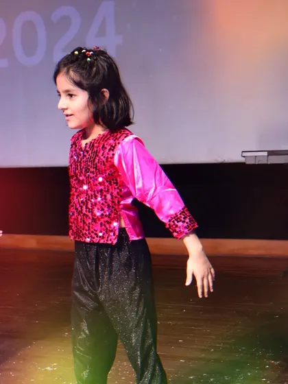 A candid shot of one of our young performers, full of expression and energy, during her group dance at Pehal.