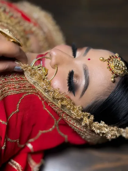 A beautiful close-up of a bride with a soft smokey eye and red lehenga. This image highlights the flawless base and the intricate details of the eye makeup.