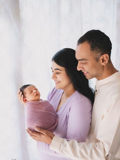 A classic family portrait with a newborn, taken against a window for soft, natural light.