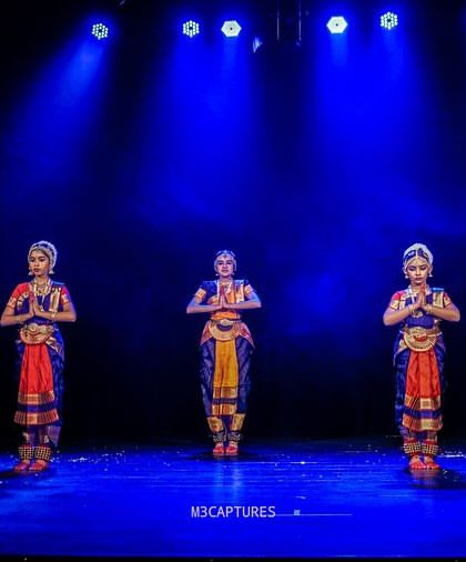A group of five students in a synchronized starting pose at the Sadhana Dance Festival, ready to begin their performance.