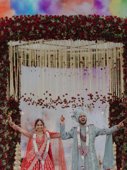 A moment of pure celebration as the couple rejoices under a shower of rose petals. Their joyful expressions and outstretched arms perfectly capture the triumphant feeling of being married.