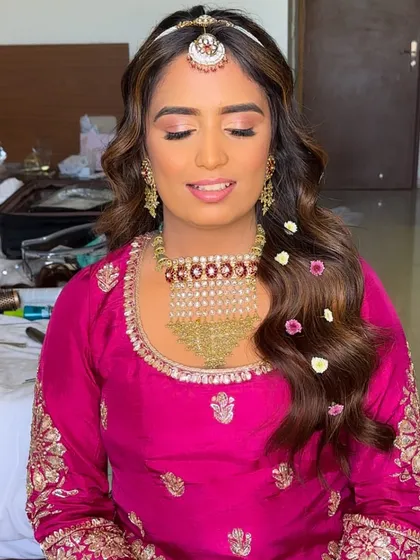 The bride looking serene with her hair in gentle waves, decorated with tiny flowers that complement her pink suit.