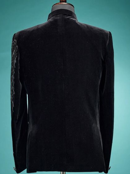 The back view of a black velvet Jodhpuri jacket, showing the clean lines and luxurious texture of the fabric.