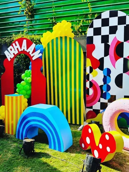 A whimsical photo backdrop with abstract shapes, hot air balloons, and oversized props.