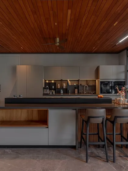 For this Ahmedabad home, we created a kitchen with architectural clarity. The handleless cabinetry in Porto Matt Lacquer provides a sleek, uninterrupted flow, while the layered island combines tactile wood shelving with bold, shadow-toned counters for a modern, sophisticated look.